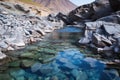 natural hot spring among smooth grey rocks