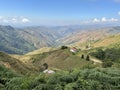 Natural landscape shows mountains with vegetation on a beautiful sunny day with blue sky and a view of houses in the distance. Royalty Free Stock Photo