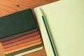 Natural leather samples variety shades of colors with notebook and pencil on wood table, designer concept. Royalty Free Stock Photo