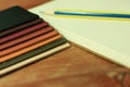 Natural leather samples variety shades of colors with notebook and pencil on wood table, designer concept.
