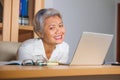 Natural lifestyle office portrait of attractive and happy successful mature Asian woman working at laptop computer desk smiling Royalty Free Stock Photo