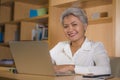 Natural lifestyle office portrait of attractive and happy successful mature Asian woman working at laptop computer desk smiling Royalty Free Stock Photo