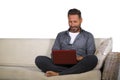 Lifestyle portrait of young handsome and successful self employed man working at home using laptop computer sitting relaxed at