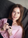 Natural light close up lifestyle portrait of beautiful blond woman with blue eyes long hair on sofa looking at camera