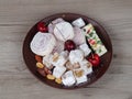 Natural lukum, peanuts, almonds, cherries in a plate on a wooden background, top view. Template for fresh Turkish delight sweets