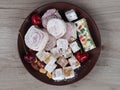 Natural lukum, peanuts, almonds, cherries in a plate on a wooden background, top view. Template for fresh Turkish delight sweets