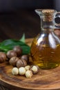 Natural macadamia oil in a glass bottle with macadamia nuts on wooden board.