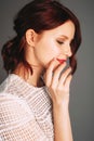 Studio portrait of young beautiful ginger woman in white lace blouse on grey background. Royalty Free Stock Photo