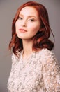 Studio portrait of young beautiful ginger woman in white lace blouse on grey background. Royalty Free Stock Photo