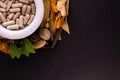 Natural medicine concept. Close-up of ayurvedic capsules in a mortar and different spices, green leaves on black background with