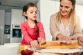 She is a natural. a middle aged mother and her daughter preparing a pizza to go into the oven in the kitchen at home. Royalty Free Stock Photo