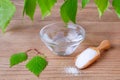 Natural mouthwash bowl with xylitol water and wood scoop with birch sugar and leafs on wooden Royalty Free Stock Photo