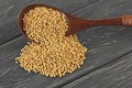 Natural mustard seeds on wooden spoon on wooden board