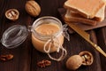 Natural nut butter in a glass jar a golden knife walnuts and sandwiches with toast on a wooden brown background. Vegetarian