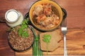 Natural organic buckwheat porridge in a clay pot, meat in a pot, a jug of milk and onions with parsley, top view. Royalty Free Stock Photo