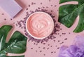 Natural organic cosmetics: body cream, bath salt, lavender soap and washcloth with monstera leaves on a pink background. Flat lay Royalty Free Stock Photo