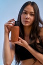 Natural and organic. Vertical shot of a young attractive asian woman holding cosmetic product and looking at camera