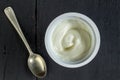 Natural organic white yogurt, Greek yogurt, plastic cup with white yoghurt on black background - overhead photo