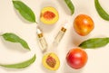 Natural peach oil. Two bottles with essential peach oil, peaches and green peach leaves on a beige background. Natural cosmetics Royalty Free Stock Photo