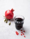 Natural pomegranate juice in a glass on a light background with fresh fruit. A healthy freshly squeezed drink with vitamins and