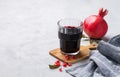 Natural pomegranate juice in a glass on a light background with fresh fruit and napkin. A healthy freshly squeezed drink with