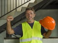 Natural portrait of young attractive and happy builder man or constructor posing cheerful smiling in blue collar job lifestyle and Royalty Free Stock Photo