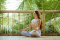 Young attractive and happy relaxed woman sitting in lotus yoga position doing meditation and concentration outdoors at wooden hut Royalty Free Stock Photo