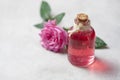 Natural pure rose oil or scented water in bottles for spa, skin care or aromatherapy. Glass bottle on a wooden table, small pink