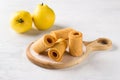 Natural quince pastille on a wooden board surrounded by fresh quince fruits on a light gray background