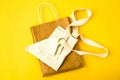 Natural reusable linen fabric and craft paper bags for shopping on yellow background with copy space