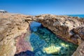 Natural rock arch over a tidal pool at the seaside Royalty Free Stock Photo