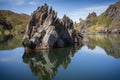 natural rock formation jutting out of a tranquil lake