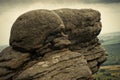 A natural rocks formation with a view of the green fields of the Royalty Free Stock Photo