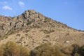 Natural rocky hill in daylight, plants and clear blue sky in the background