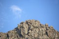 Natural rocky hill in daylight, plants and clear blue sky in the background