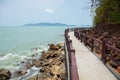 Natural scenic shot of rocky cliff with greenery tree on the sea and ocean wave which the walking path bridge shows beauty tourism Royalty Free Stock Photo