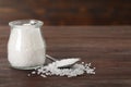 Natural sea salt, glass jar and spoon on wooden table. Space for text