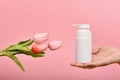 Natural skincare bottle, Hand showing cosmetic containers packaging with tulip flower essence extract