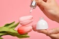 Natural skincare bottle, Hand showing dropping cosmetic containers packaging with tulip flower essence extract