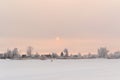 Natural snow-covered landscape with rising sun in frost, winter at dawn. Fisherman walking on the river in the distance