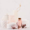 Natural spa cosmetics with pink rose oil, salt, soap and lavender flowers closeup on white wood background, interior, border. Royalty Free Stock Photo