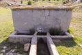 Natural spring water flowing from the pipe and the water trough Royalty Free Stock Photo