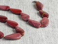 Natural stone, irregularly shaped red jasper beads on burlap background. Close-up Royalty Free Stock Photo