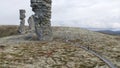 Natural stone sculptures on a hill top on cloudy sky background. Clip. A man looking very small near giant stone pillars Royalty Free Stock Photo