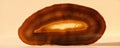 Natural stone slice with brown layers and a light center displayed on a plain surface for commercial use Royalty Free Stock Photo