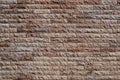 Natural stone wall made of rough brownish pink rock bricks. Royalty Free Stock Photo