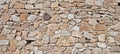 Natural stones form wall structure with various sizes and colors in outdoor setting during daylight Royalty Free Stock Photo