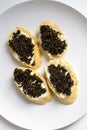 Natural sturgeon black caviar sandwiches on a white plate, luxury seafood delicacy Royalty Free Stock Photo