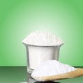 Natural sugar powder in container and wooden spoon in green background