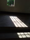 Sunlight streaming through window creating geometric shadow patterns on staircase floor Royalty Free Stock Photo